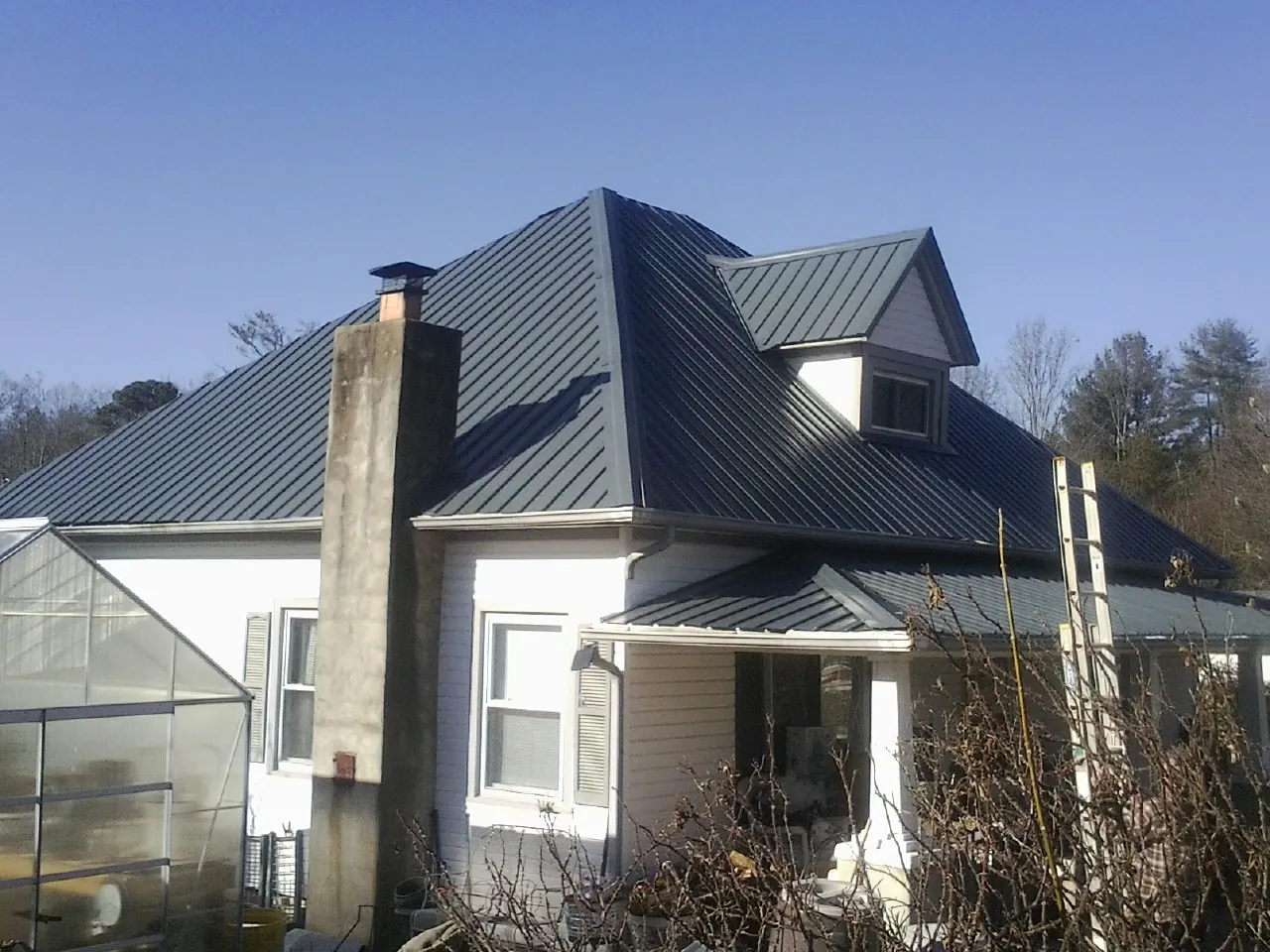 Dark blue standing seam metal roof on a white farmhouse with dormer — Slate & Tile Roof Repair by Roofing Brothers in Waucoma