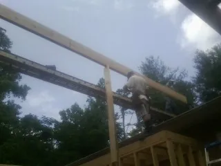 Carpenter setting a ridge beam over a new addition frame — Ice Dam Removal by Roofing Brothers in Waucoma