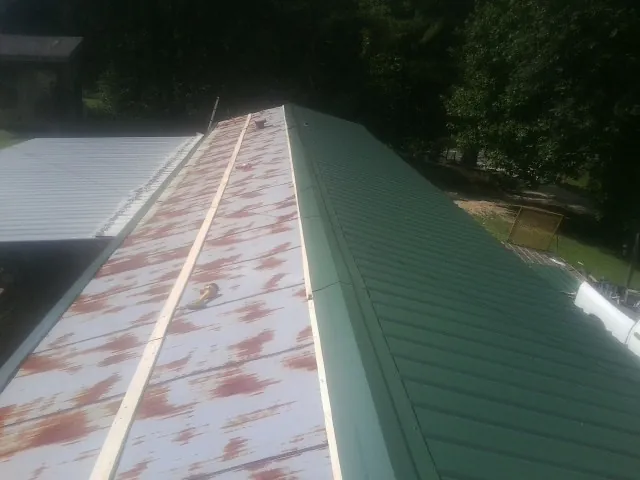 Old rusted panels beside newly installed green metal roofing — Wind Damage Roof Repair by Roofing Brothers in Waucoma