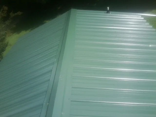 New green metal panels meeting at the ridge of a roof — Flat Roof Repair work by our crew in Waucoma