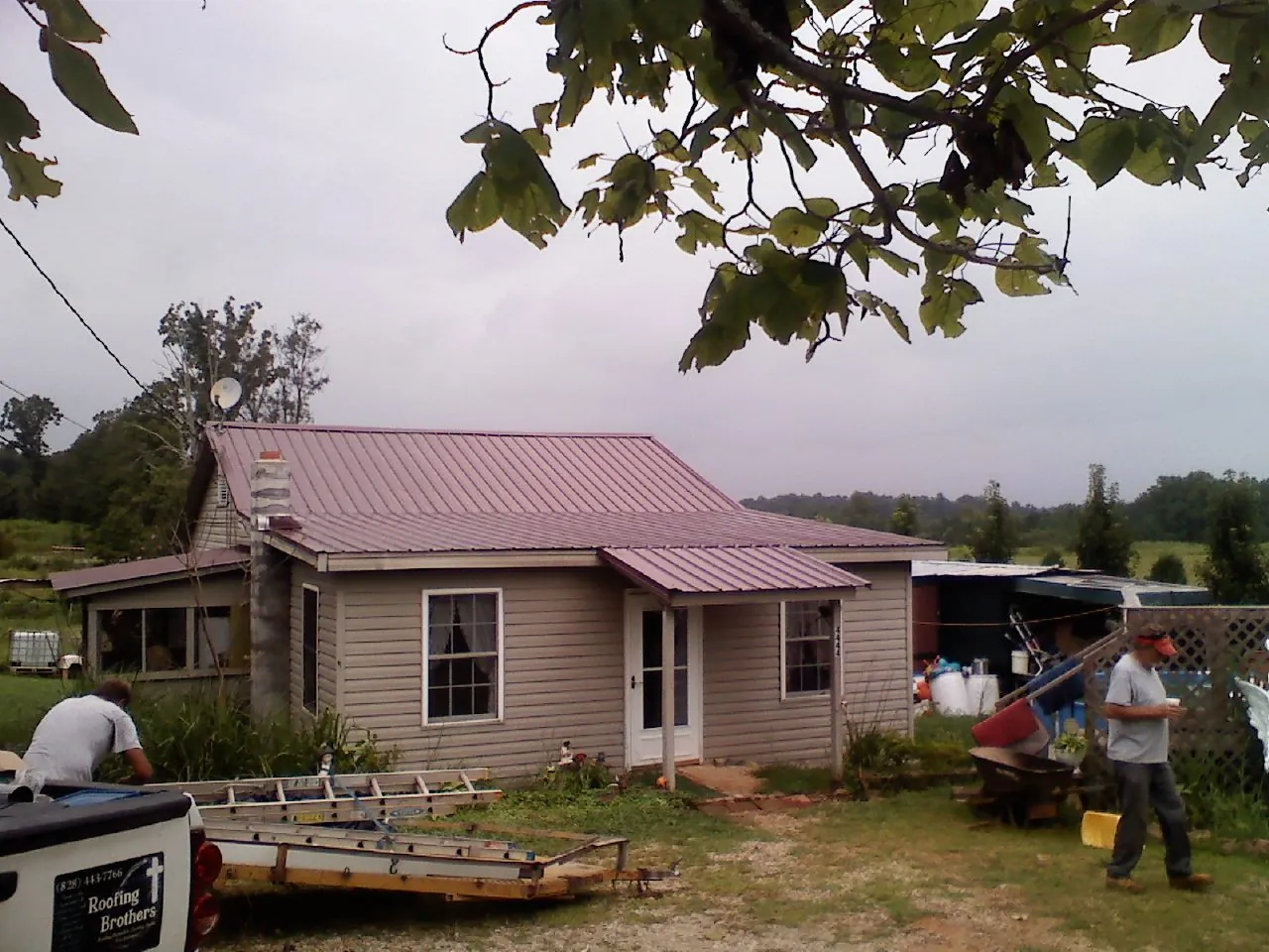 Crew finishing a mauve metal roof on a small farmhouse in Waucoma