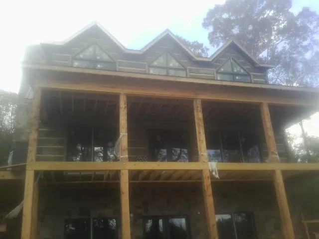 Dormers and porch framing on a large log home under construction — Roof Coating work by our crew in Waucoma