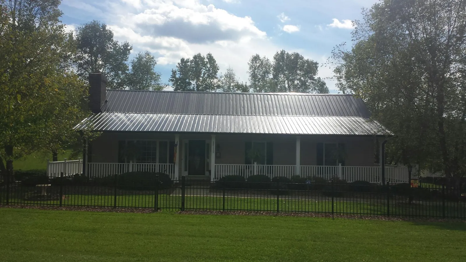 Gray metal roof on a brick ranch with a full width front porch — Gutter Guard Installation work by our crew in Waucoma
