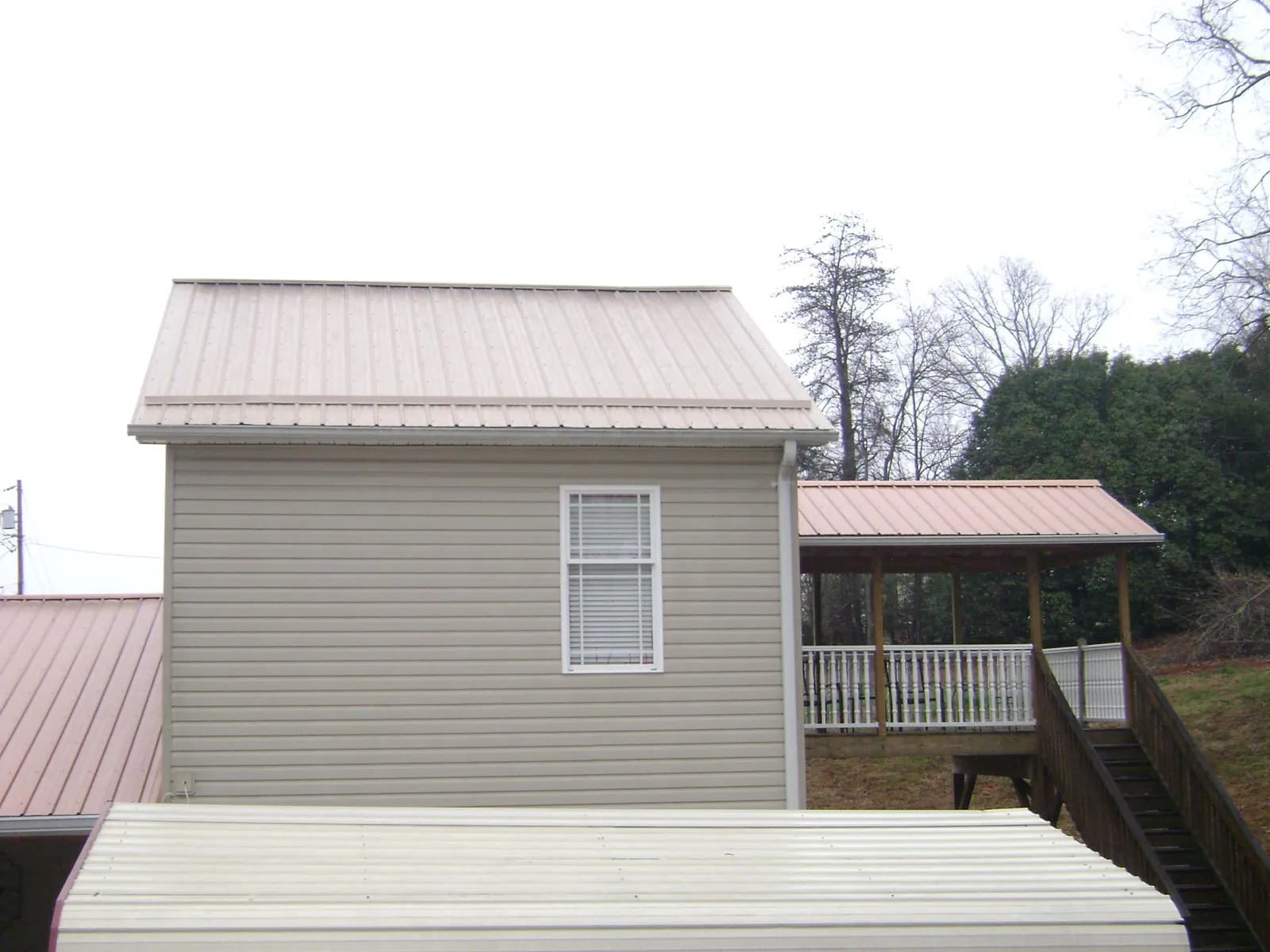 Tan metal roofs on a two story addition and attached porch, from a Roof Replacement job in Waucoma