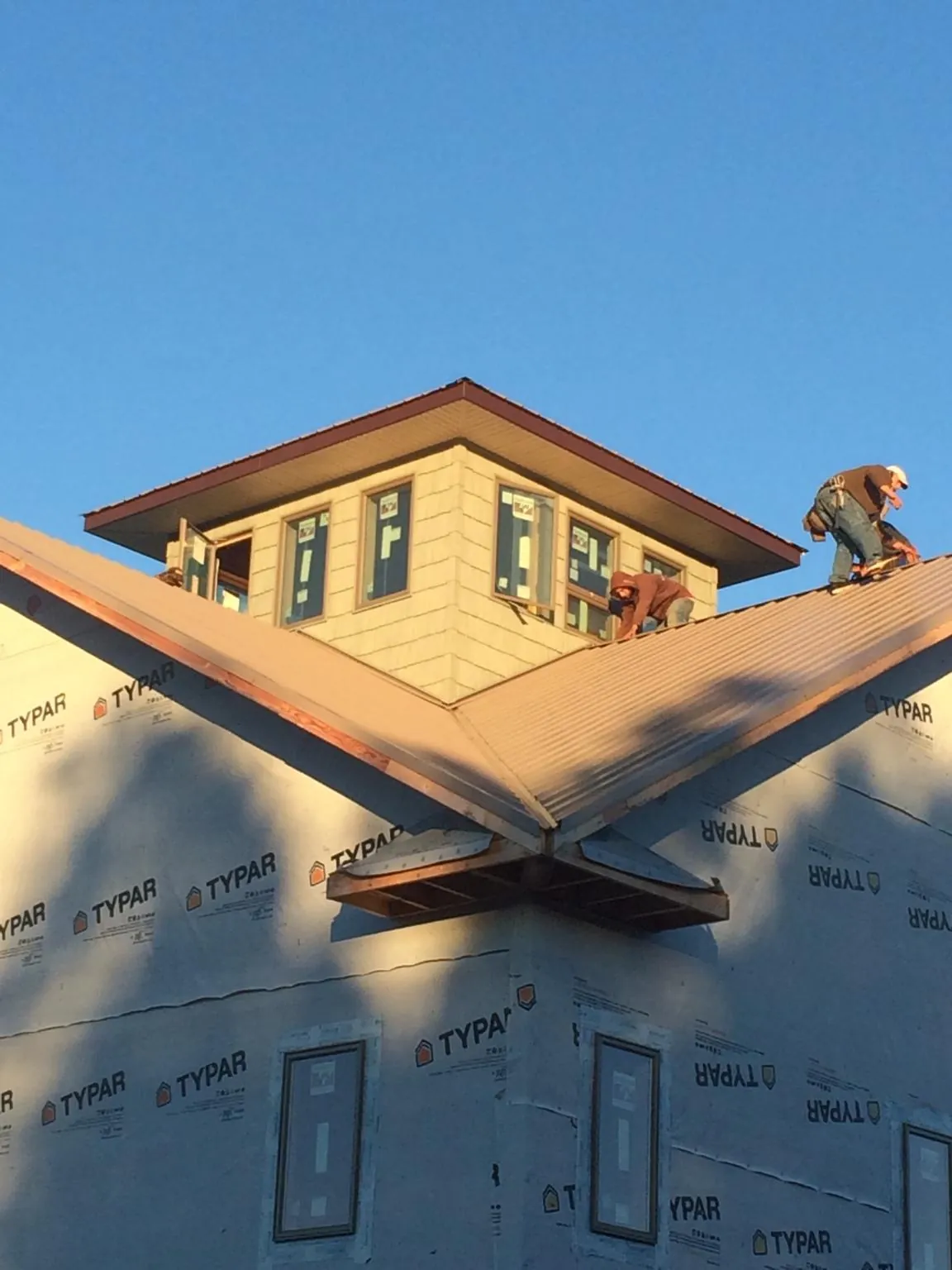 Roofers working around a rooftop cupola on a new metal roof at sunset — Roof Waterproofing in Waucoma by Roofing Brothers
